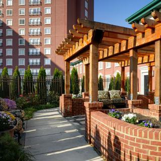 A beautifully constructed pergola with brick pillars enhances the garden area of an urban residential complex.