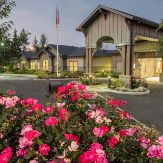 A building exterior surrounded by vibrant flowers and well-maintained landscaping in the evening.