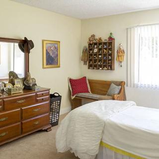 A cozy bedroom with a wooden dresser, bed, and decorative items.
