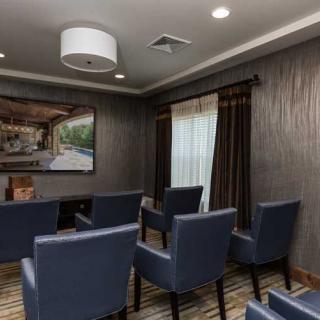A modern lounge area with blue chairs arranged for a meeting, featuring decorative wall art and carpeted flooring.