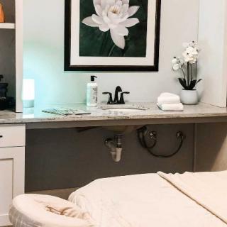 A serene massage room with a treatment bed, calming artwork, and spa essentials.