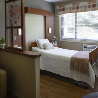 A clean and well-lit hospital room with a single bed and large window.