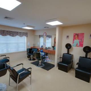 A well-lit hair salon equipped with chairs, mirrors, and hair dryers.