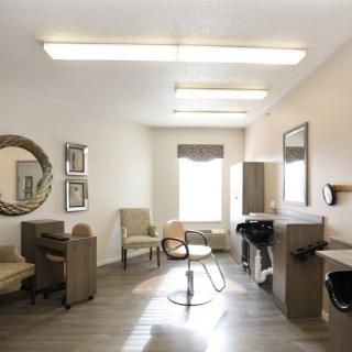 A bright and modern salon interior with chairs, a mirror, and a hair wash station.