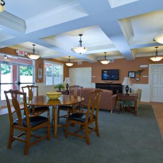 A cozy living room with a dining table and wooden chairs, featuring elegant pendant lighting and a stylish ceiling design.