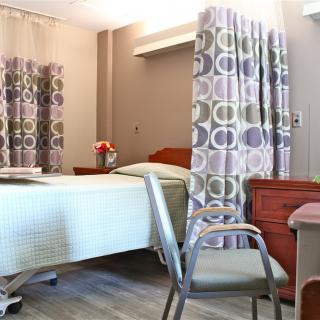 A neatly arranged hospital room with a bed, chair, and privacy curtains.