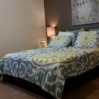 A cozy bedroom with a patterned bedspread and a bedside lamp.