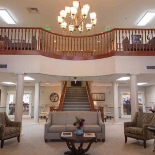 An elegant lobby with a grand staircase, chandelier, and comfortable seating area.