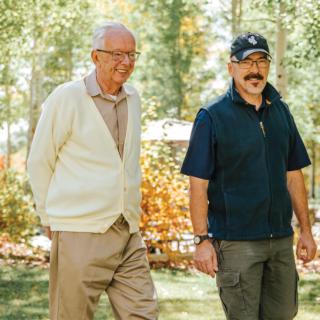 Two men walking together in a park-like setting.