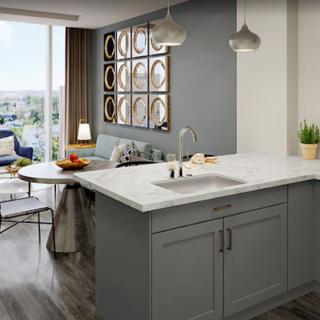 A modern kitchen with an island counter seamlessly connects to a cozy living room, showcasing a stylish open-concept design with ample natural light.