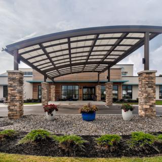 Modern building entrance with a stylish awning and landscaped surroundings.