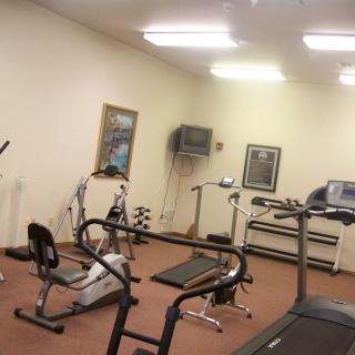 A small gym with various exercise equipment, including a treadmill and stationary bike.