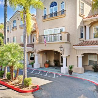 A sunny view of a residential building with palm trees at the entrance.