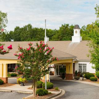 A picturesque building entrance surrounded by trees and neatly arranged landscaping.