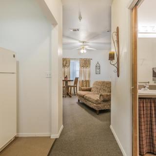 A cozy apartment hallway leading to a furnished living room with a sofa and ceiling fan.