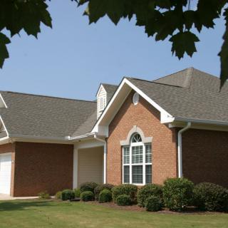 A suburban brick house with a well-kept lawn and attached garage.