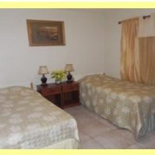 A cozy bedroom with two twin beds, a nightstand with lamps, and a painting on the wall.