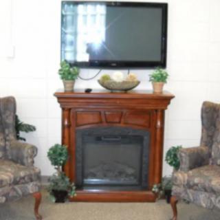 A cozy living room setup featuring a central fireplace, a TV mounted above it, and two patterned chairs on either side.