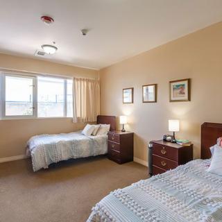 A neatly arranged bedroom with twin beds and warm lighting.