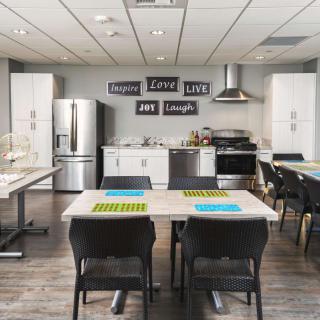 A modern kitchen and dining area featuring stainless steel appliances, stylish decor, and neatly arranged tables and chairs.