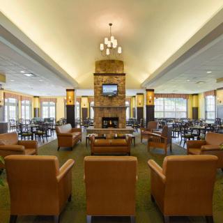 A spacious lounge area featuring comfortable seating, a central fireplace, and a mounted television.