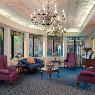 A well-lit lobby with elegant chandeliers, comfortable seating, and large windows.