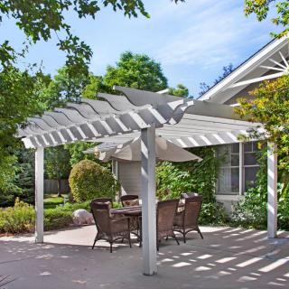 A tranquil backyard patio with a white pergola providing shade over a seating area.