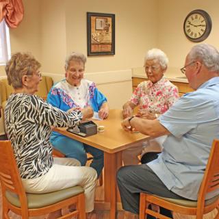 A group of seniors enjoying a card game at a table indoors.