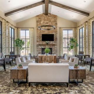 A spacious and elegantly designed living room with a vaulted ceiling, stone fireplace, modern furniture, and large windows that allow natural light to fill the space.