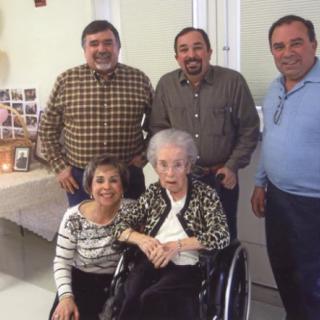A family group photo features an elderly woman in a wheelchair surrounded by four other family members.