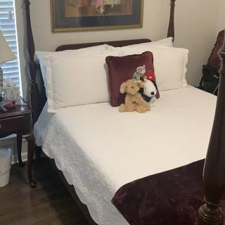 A neatly made bed with decorative pillows and stuffed animals in a cozy bedroom.