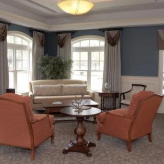 A cozy living room with a sofa, two armchairs, and a coffee table set against large windows and elegant curtains.