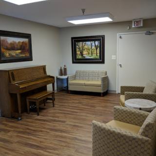 A cozy lounge area featuring a piano, comfortable seating, and framed artwork.