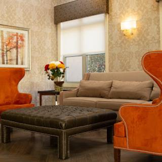 A cozy living room featuring vibrant orange armchairs, a brown sofa, and a stylish coffee table adorned with flowers.