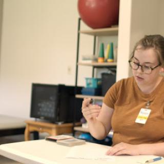 A person is focused on their work at a table, engaged in writing or drawing.