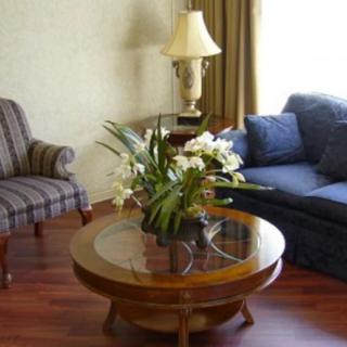 A cozy living room with a blue sofa, striped armchair, and a round wooden coffee table adorned with a floral arrangement.