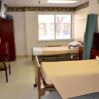 A hospital room with two beds, a window, and medical equipment.