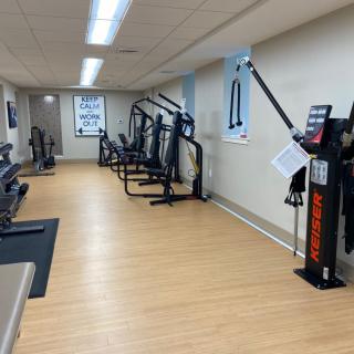 A well-equipped gym with various exercise machines lined up against the wall.