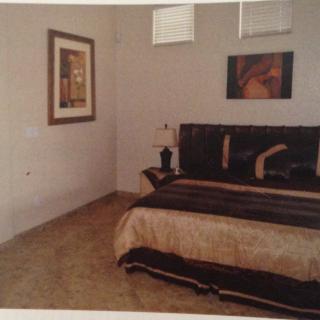 A cozy bedroom with artwork on the walls and a neatly made bed.