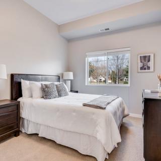 A cozy bedroom with a neatly made bed, modern furniture, and a window offering natural light.