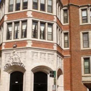 A multi-story brick building with large windows and arched entrances.
