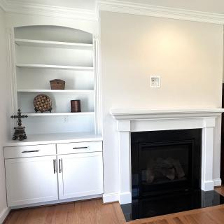 A cozy living room space with a white fireplace and built-in shelving, featuring decorative items.