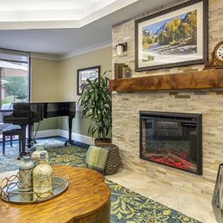 A cozy living room featuring a fireplace, grand piano, and elegant decor.