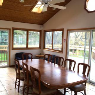 A spacious dining area with a wooden table and chairs, surrounded by large windows that let in abundant natural light.