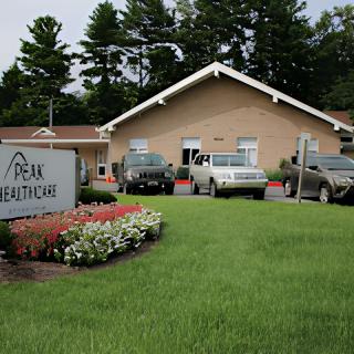 A healthcare facility with parked cars and a well-maintained lawn.