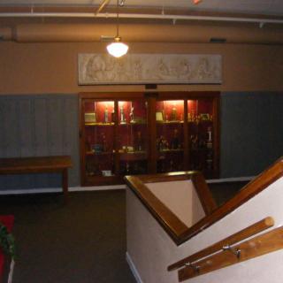 A dimly lit hallway featuring a staircase and a display case.