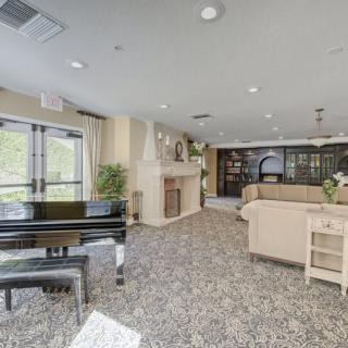 A spacious lobby area with a grand piano, sofas, and a fireplace.