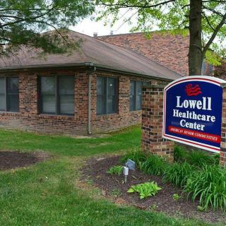 A brick healthcare center with a sign that reads 'Lowell Healthcare Center', surrounded by grass and trees.