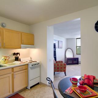A cozy apartment kitchen with a small dining table and view into the living room.