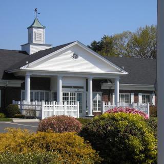 A well-manicured entrance to a building with white columns and surrounding landscaping.